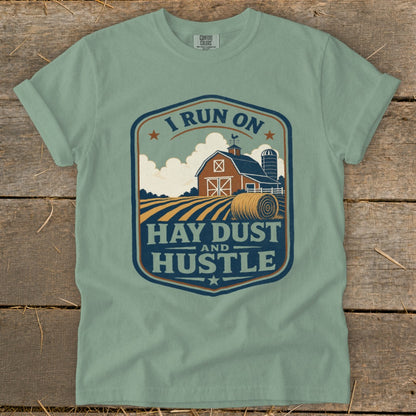Green t-shirt with barn, silo, hay bales, and text "I Run On Hay Dust And Hustle".