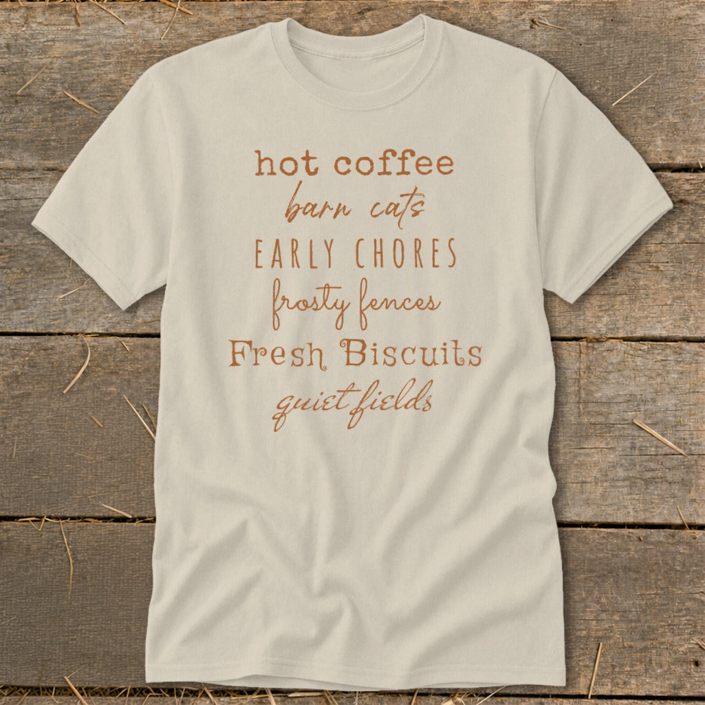 Cream t-shirt with brown text listing "hot coffee, barn cats, early chores, frosty fences, fresh biscuits, quiet fields".