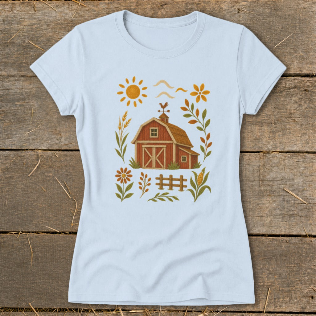 Light blue t-shirt with a barn, sun, fence, and autumn foliage graphic.