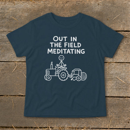 Navy t-shirt with white text "OUT IN THE FIELD MEDITATING" and a stick figure meditating on a tractor.