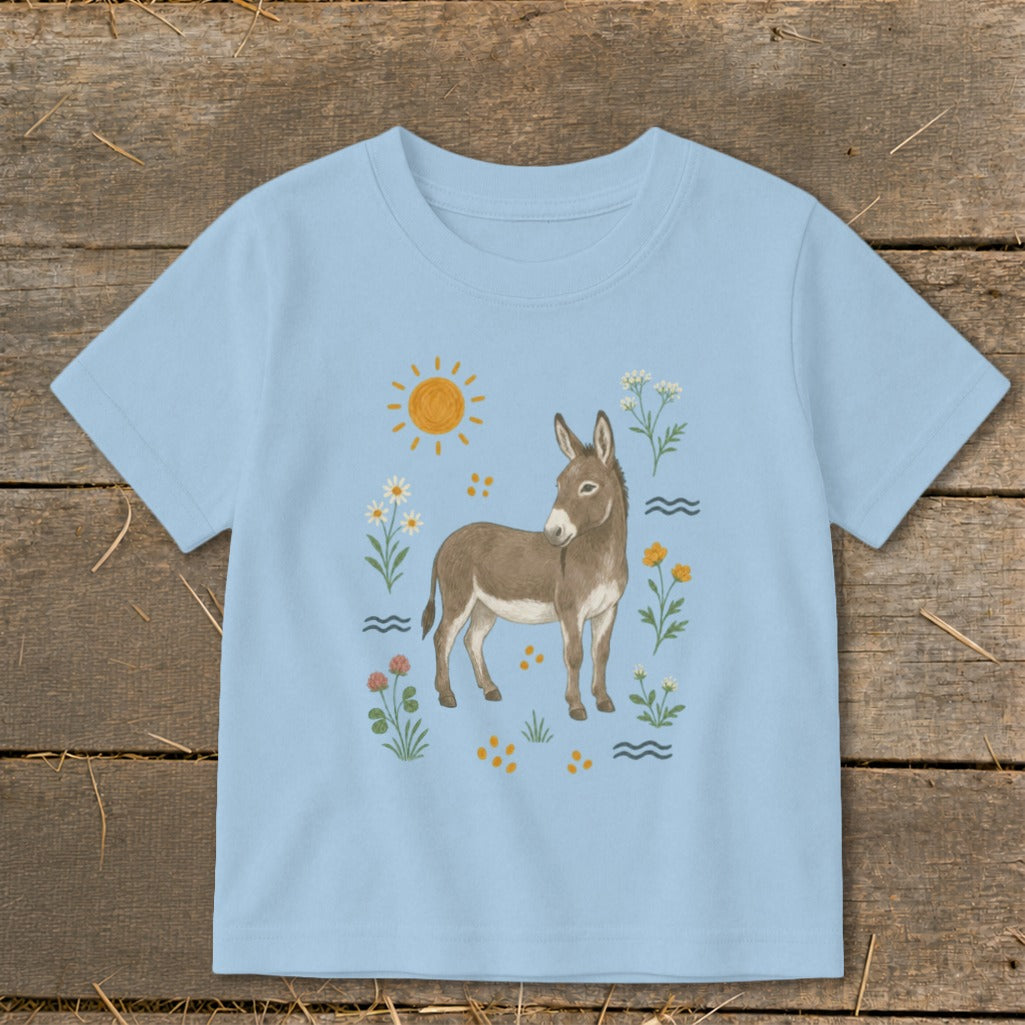 Light blue t-shirt with a watercolor-style donkey, sun, and wildflowers illustration.