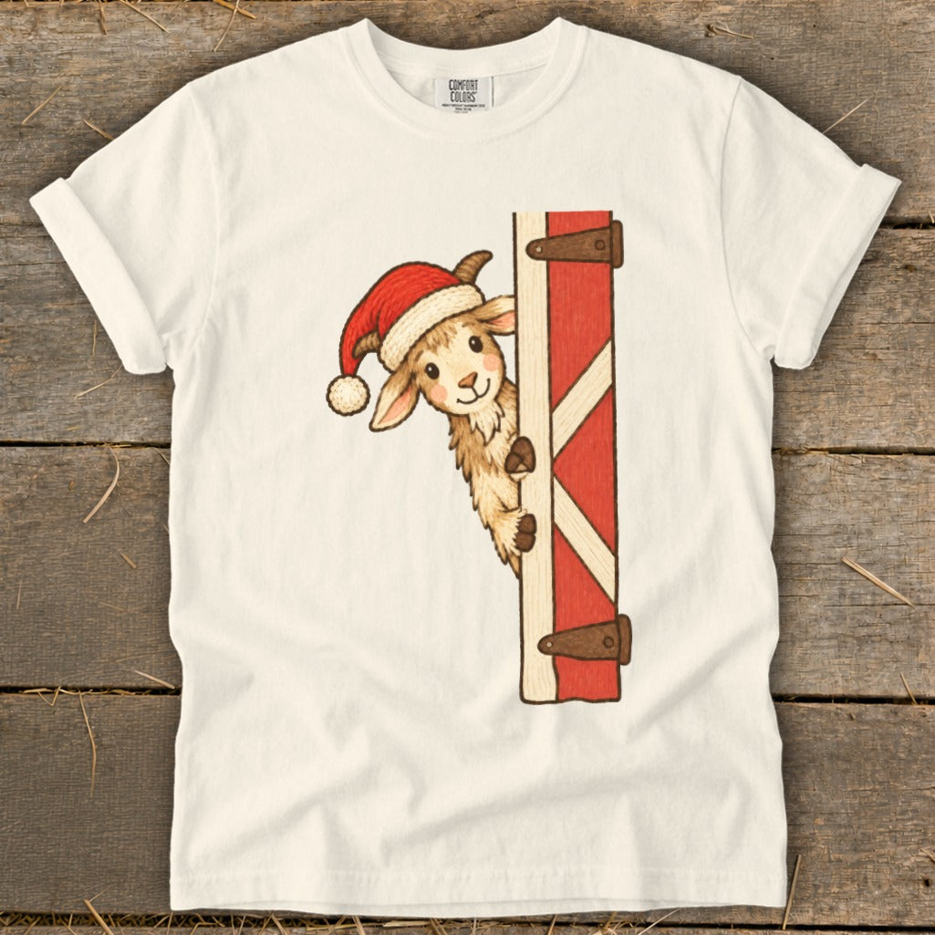 Christmas llama wearing Santa hat peeks from behind red barn door.