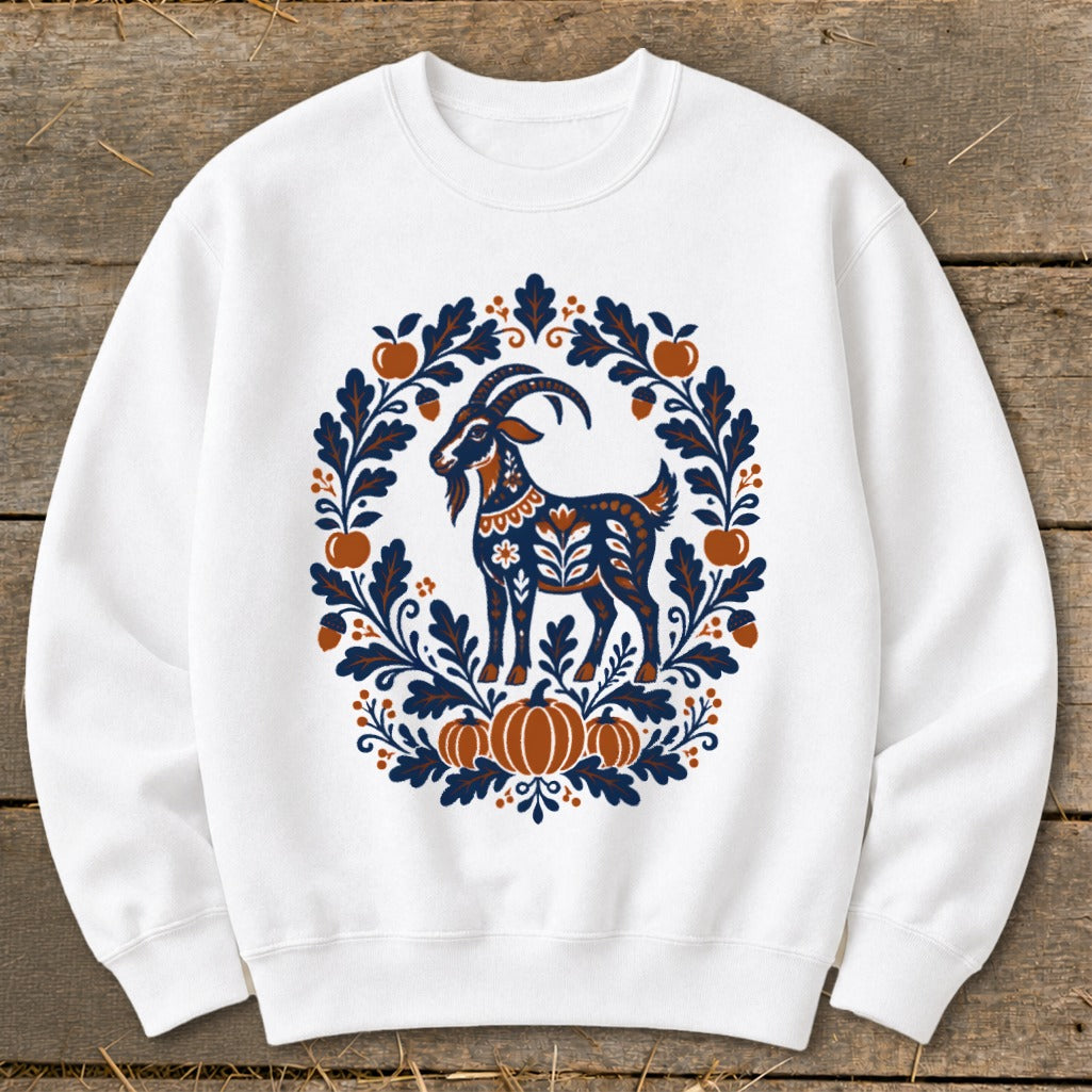 A white crewneck sweatshirt featuring a folk-art goat surrounded by a blue and orange autumn wreath.