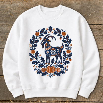 A white crewneck sweatshirt featuring a folk-art goat surrounded by a blue and orange autumn wreath.