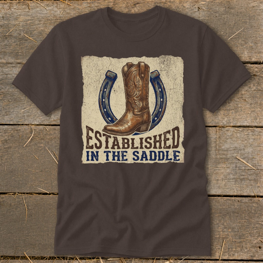 Brown t-shirt with cowboy boot, horseshoes, and text "ESTABLISHED IN THE SADDLE".