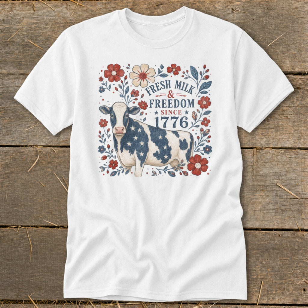 White t-shirt with patriotic cow and floral design, text "FRESH MILK & FREEDOM SINCE 1776".