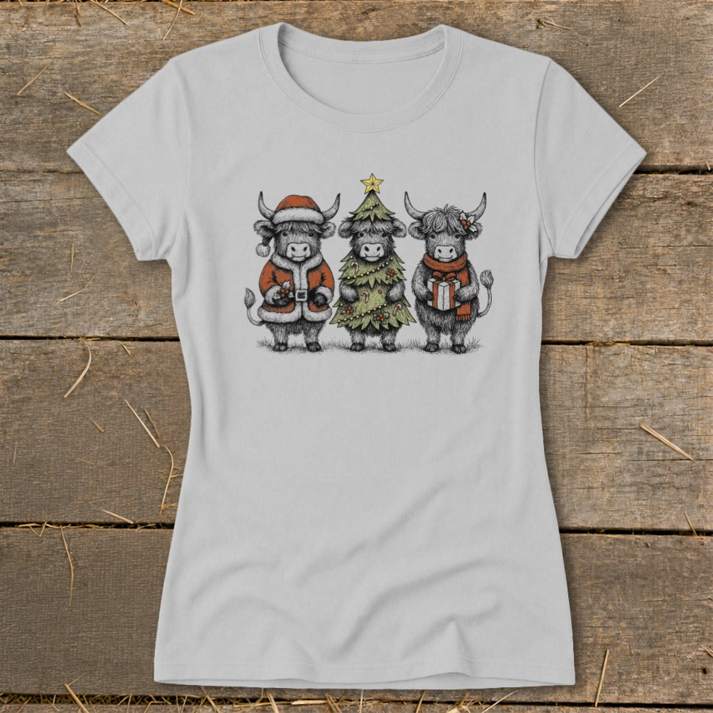 Three Highland cows wearing Christmas outfits: Santa, a tree, and holding a gift.