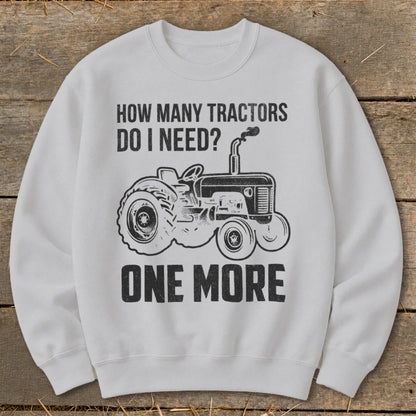 White sweatshirt with "How Many Tractors Do I Need? One More" and tractor graphic.