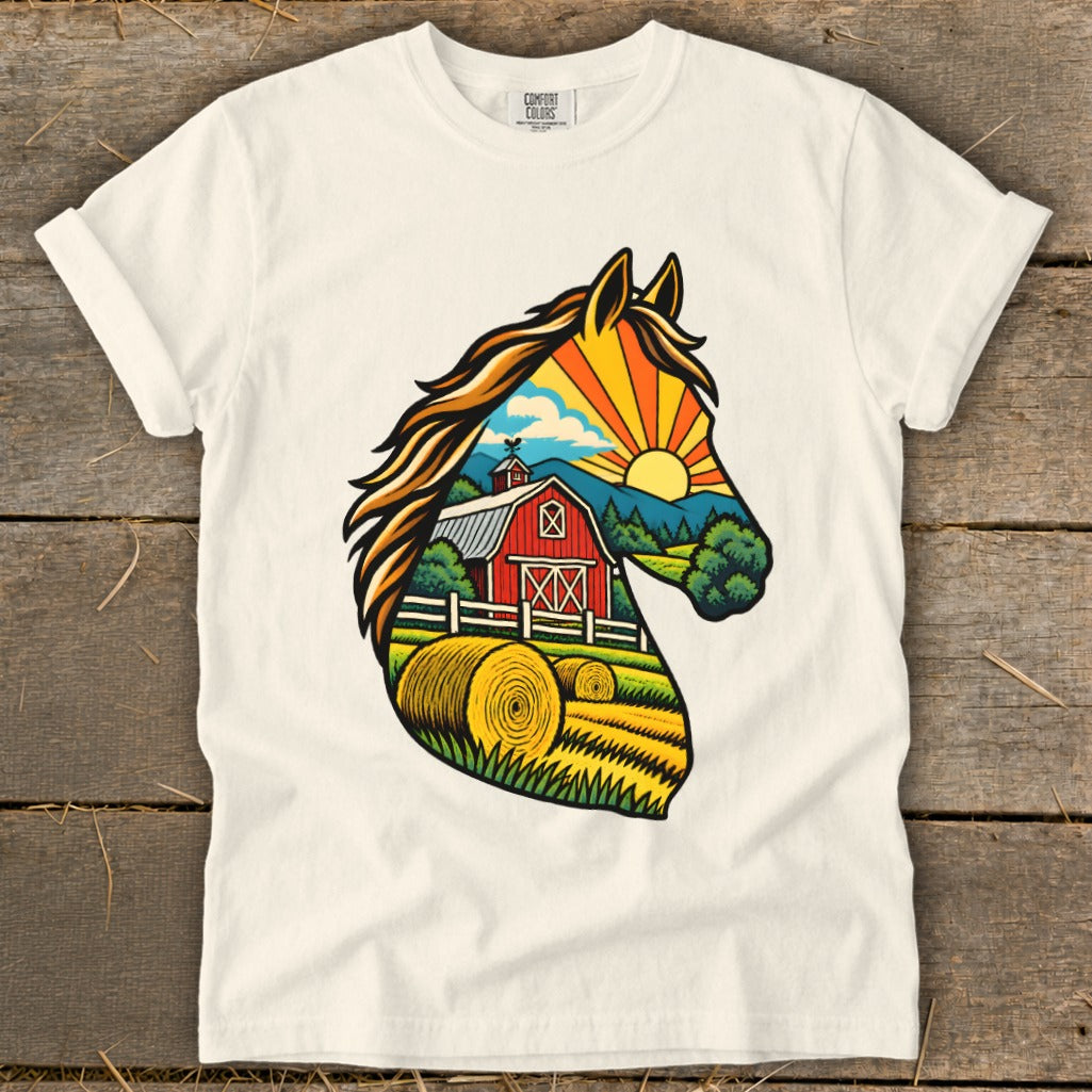 A cream-colored t-shirt displays a graphic of a horse head silhouette filled with a countryside farm scene.