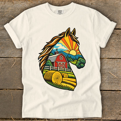 A cream-colored t-shirt displays a graphic of a horse head silhouette filled with a countryside farm scene.