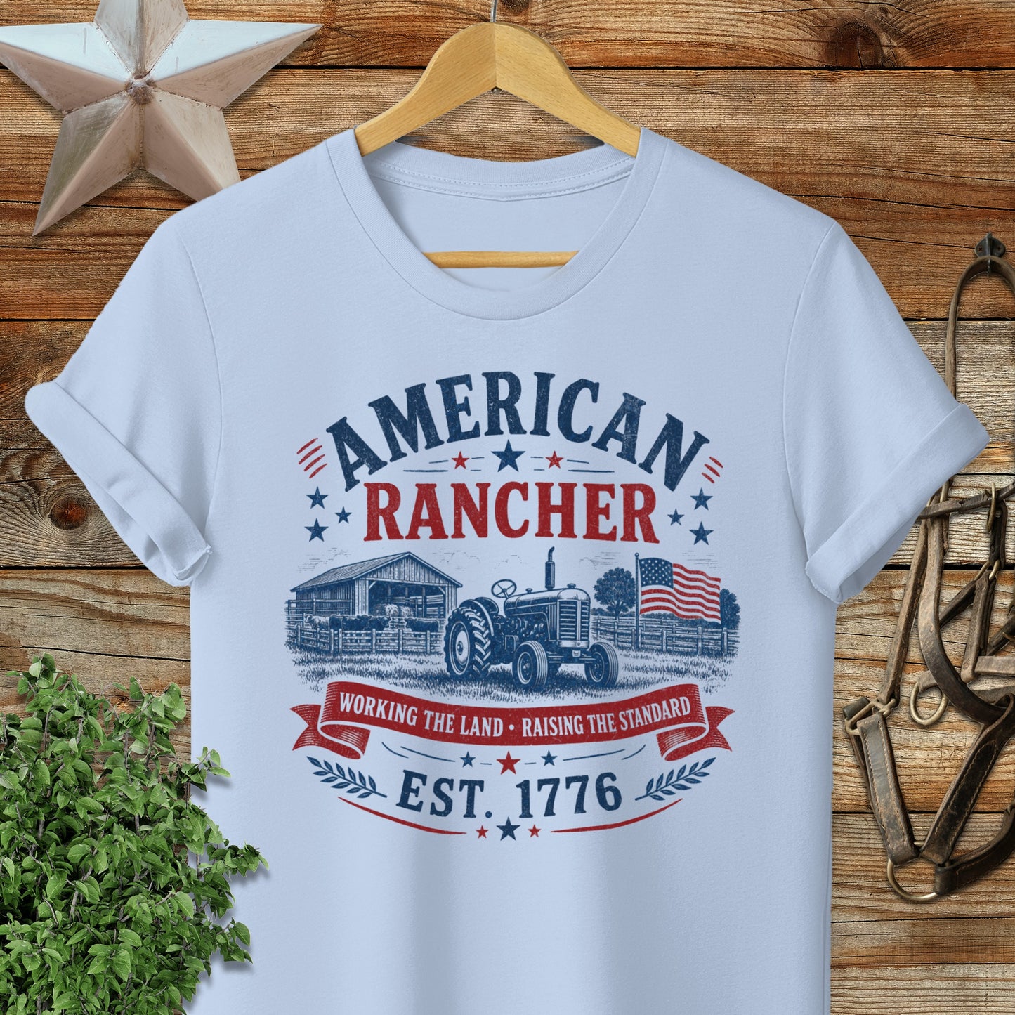 American Rancher Est. 1776 shirt with tractor, barn, and flag graphic.