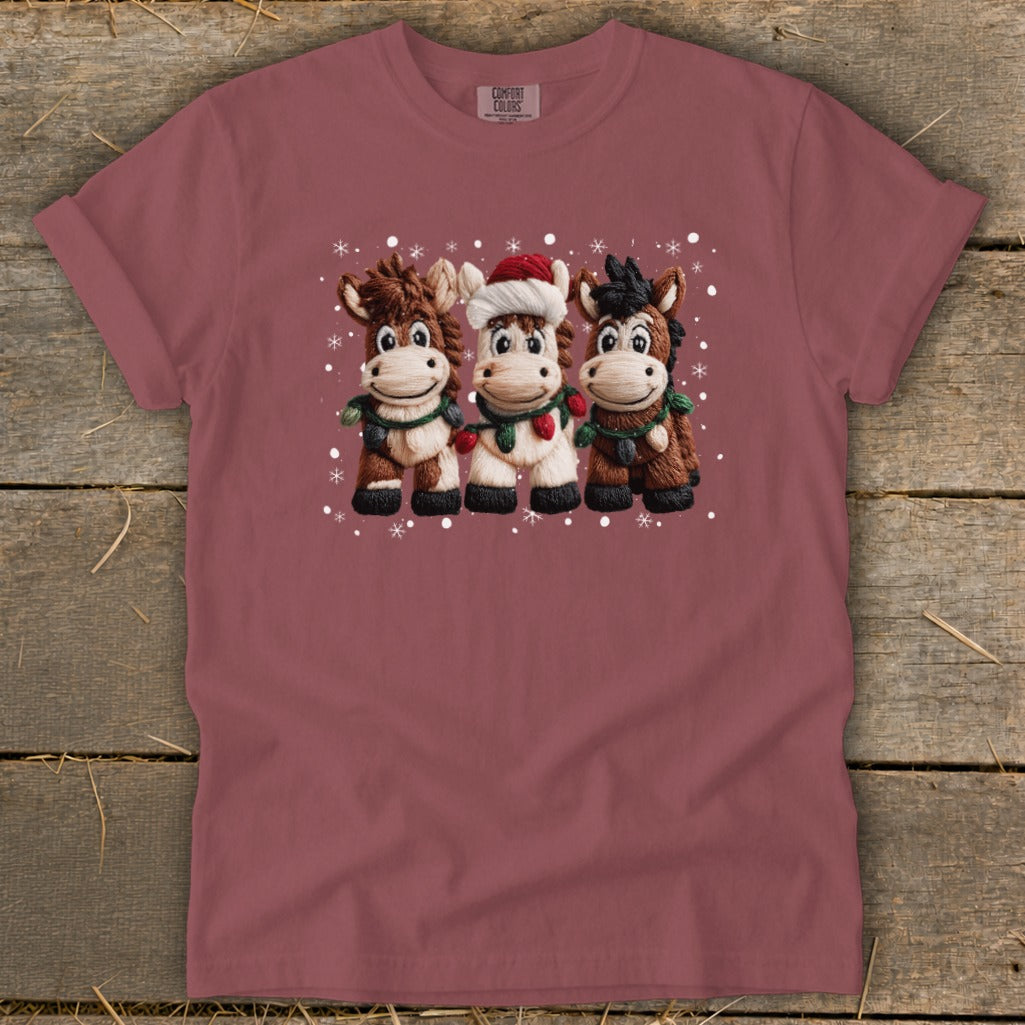 Three cartoon horses wearing holiday scarves and lights, one with a Santa hat.