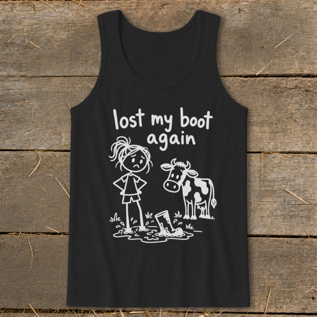 A black tank top featuring white stick-figure art of a girl looking at her boot stuck in mud alongside a cow, with the text lost my boot again above them.