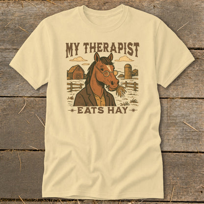 T-shirt graphic of a horse wearing glasses, eating hay, with "My Therapist Eats Hay" text.