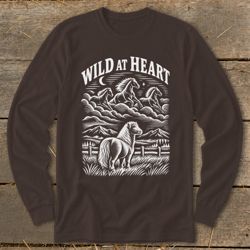 Dark brown long-sleeve t-shirt with a white graphic print featuring horses, mountains, and the text WILD AT HEART.