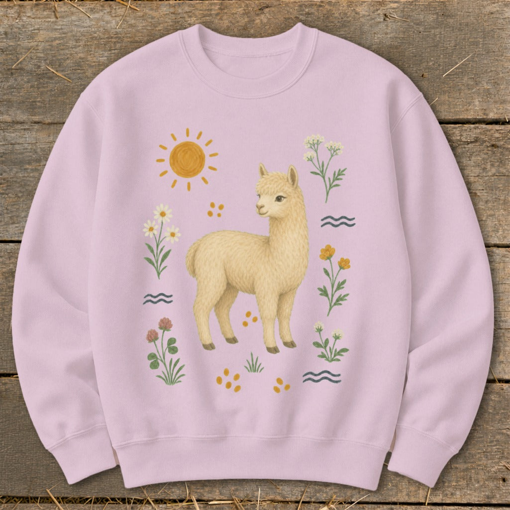 Light pink sweatshirt with a cream-colored alpaca surrounded by flowers, sun, and wavy lines.