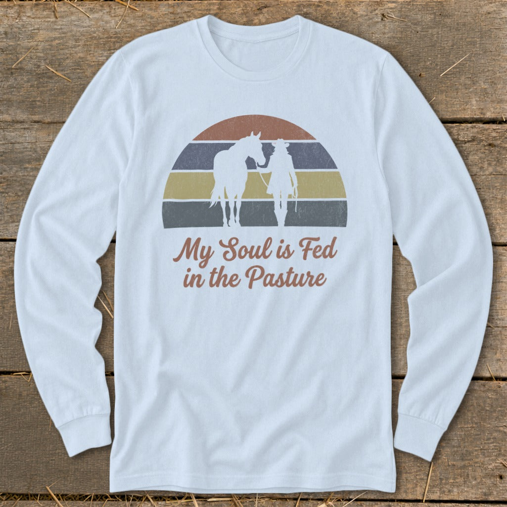 Long sleeve shirt with horse and rider silhouette and "My Soul is Fed in the Pasture" text.