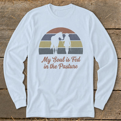 Long sleeve shirt with horse and rider silhouette and "My Soul is Fed in the Pasture" text.