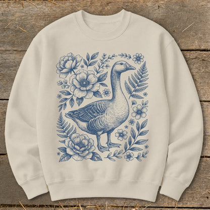 Cream sweatshirt with a blue ink drawing of a goose surrounded by flowers and ferns.
