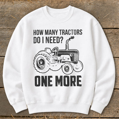 White sweatshirt with black graphic of tractor and text "HOW MANY TRACTORS DO I NEED? ONE MORE".