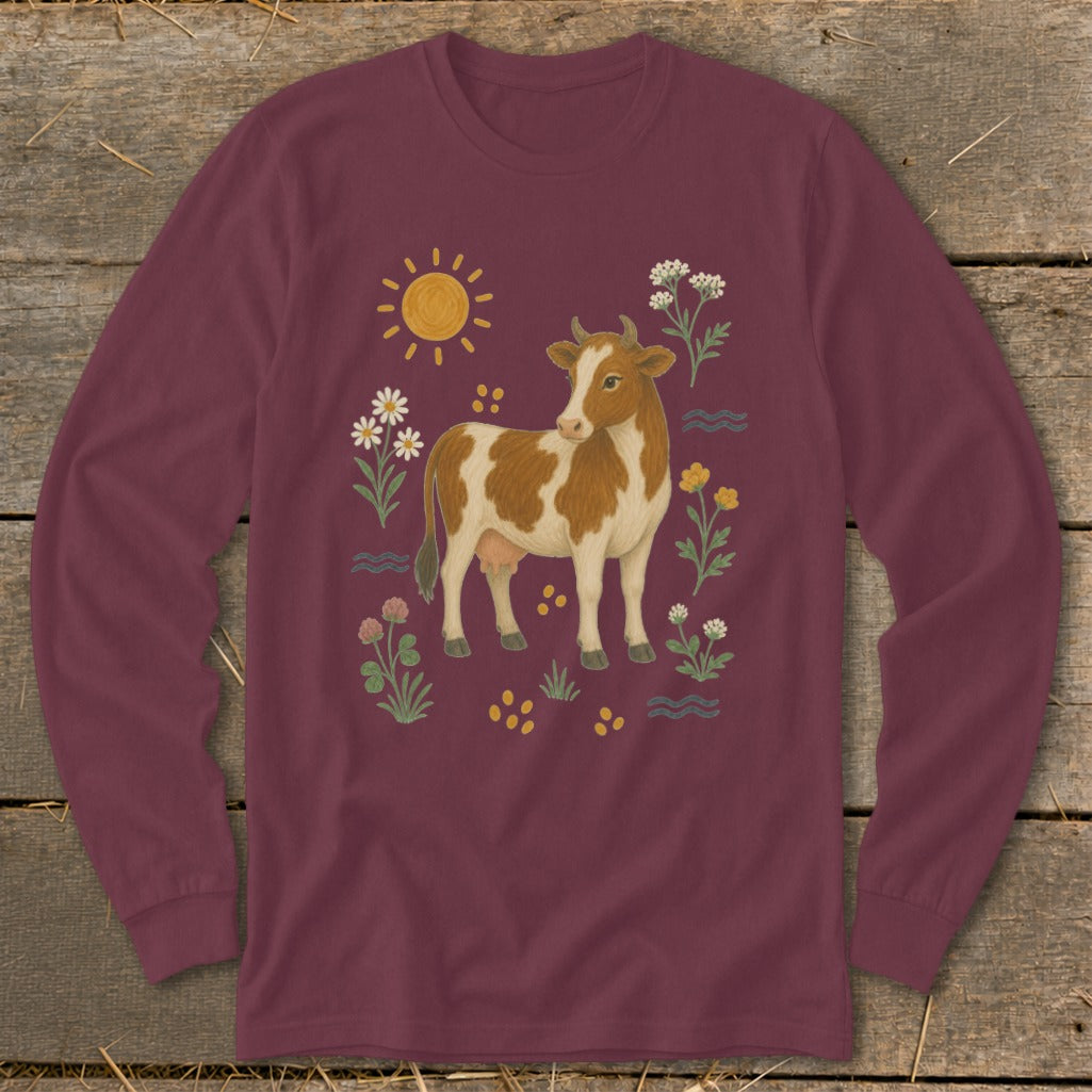 Maroon long-sleeve shirt with a brown and white cow surrounded by flowers and sun.