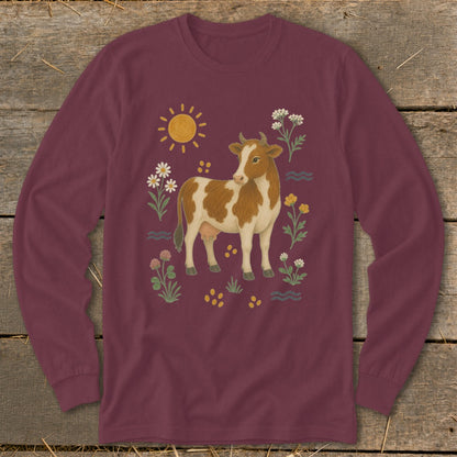 Maroon long-sleeve shirt with a brown and white cow surrounded by flowers and sun.