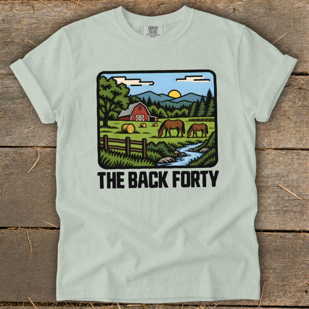 A light green t-shirt featuring a pastoral farm graphic with horses and the text The Back Forty.