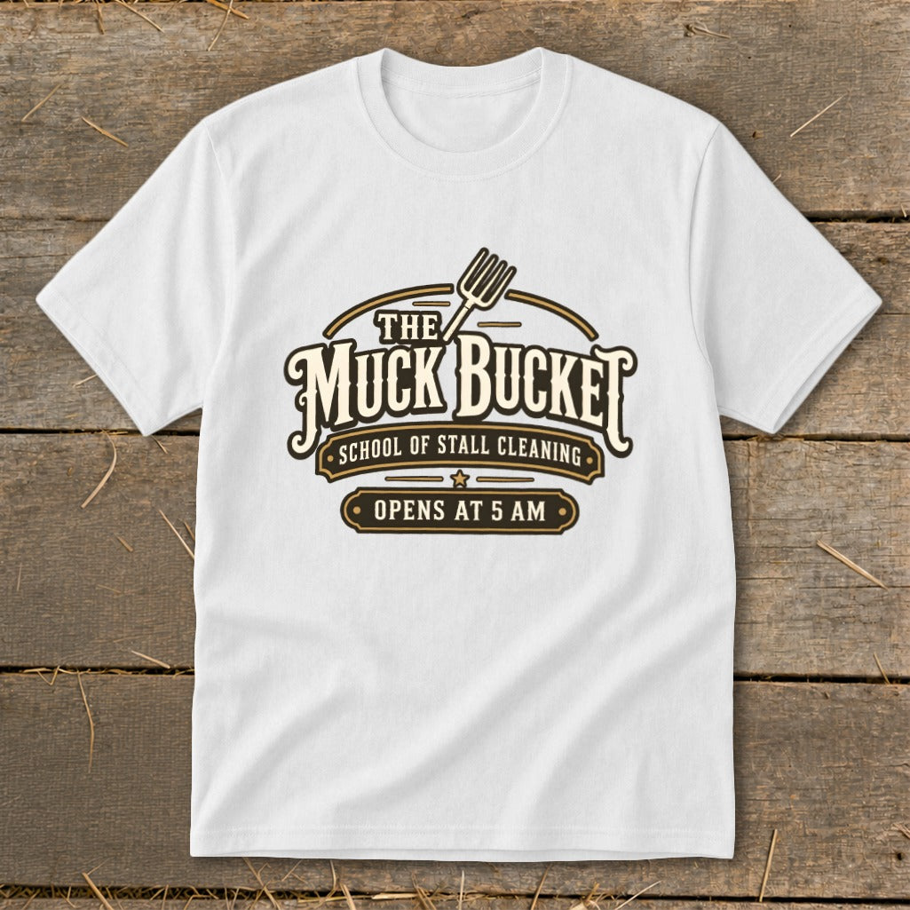 White t-shirt with "The Muck Bucket School of Stall Cleaning Opens at 5 AM" logo.