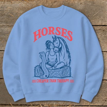Light blue sweatshirt with graphic "Horses Cheaper Than Therapy" and illustration of woman and horse.