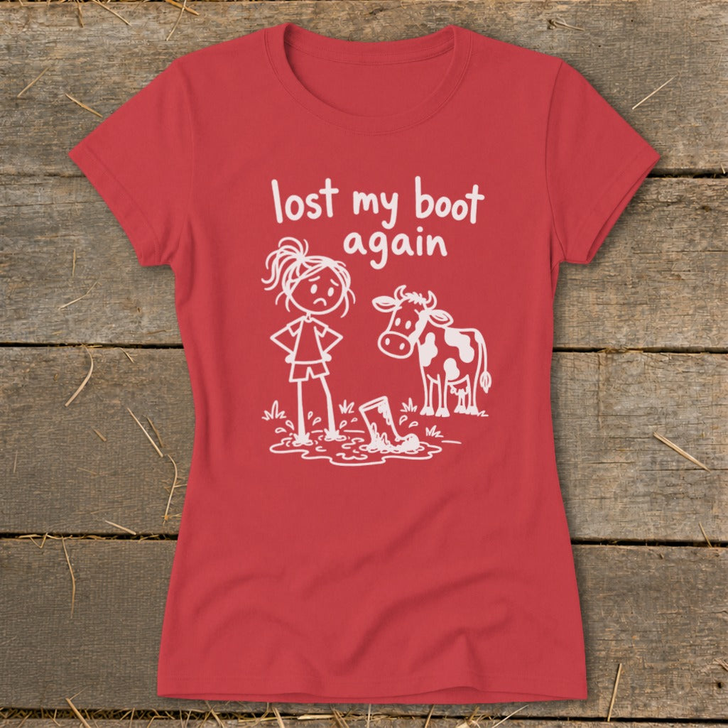 Red women's t-shirt featuring a white graphic of a girl and a cow beside a muddy boot, with text reading lost my boot again.