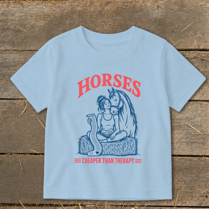 Light blue t-shirt graphic with "HORSES CHEAPER THAN THERAPY" and a woman with a horse holding a vet bill.