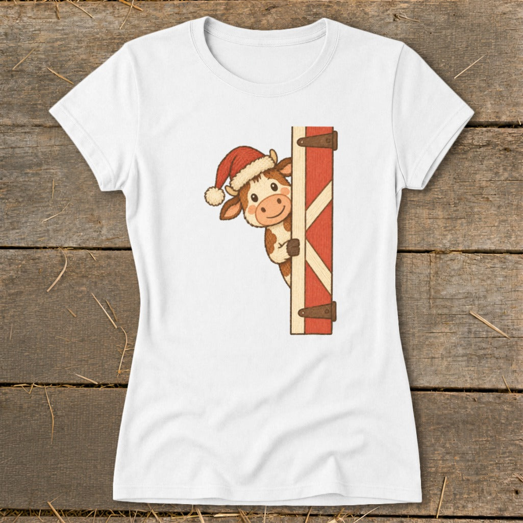 White t-shirt with a cartoon cow wearing a Santa hat peeking from behind a red barn door.