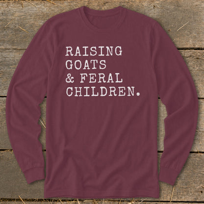 Maroon long-sleeve shirt with white text: Raising goats & feral children.