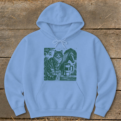 Light blue hoodie with a green linocut design of a cat, horse, and mug.