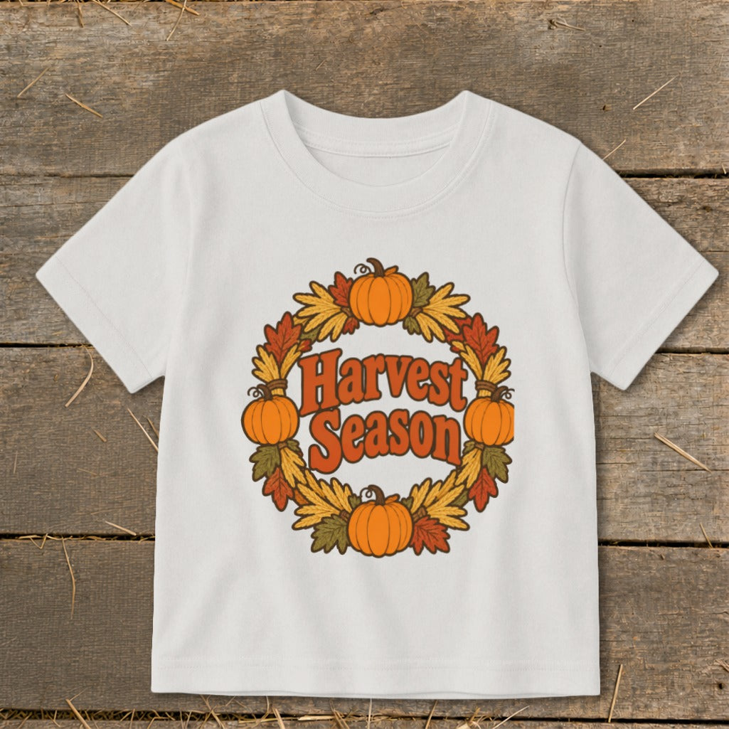 White t-shirt with "Harvest Season" text and a pumpkin and leaf wreath graphic.