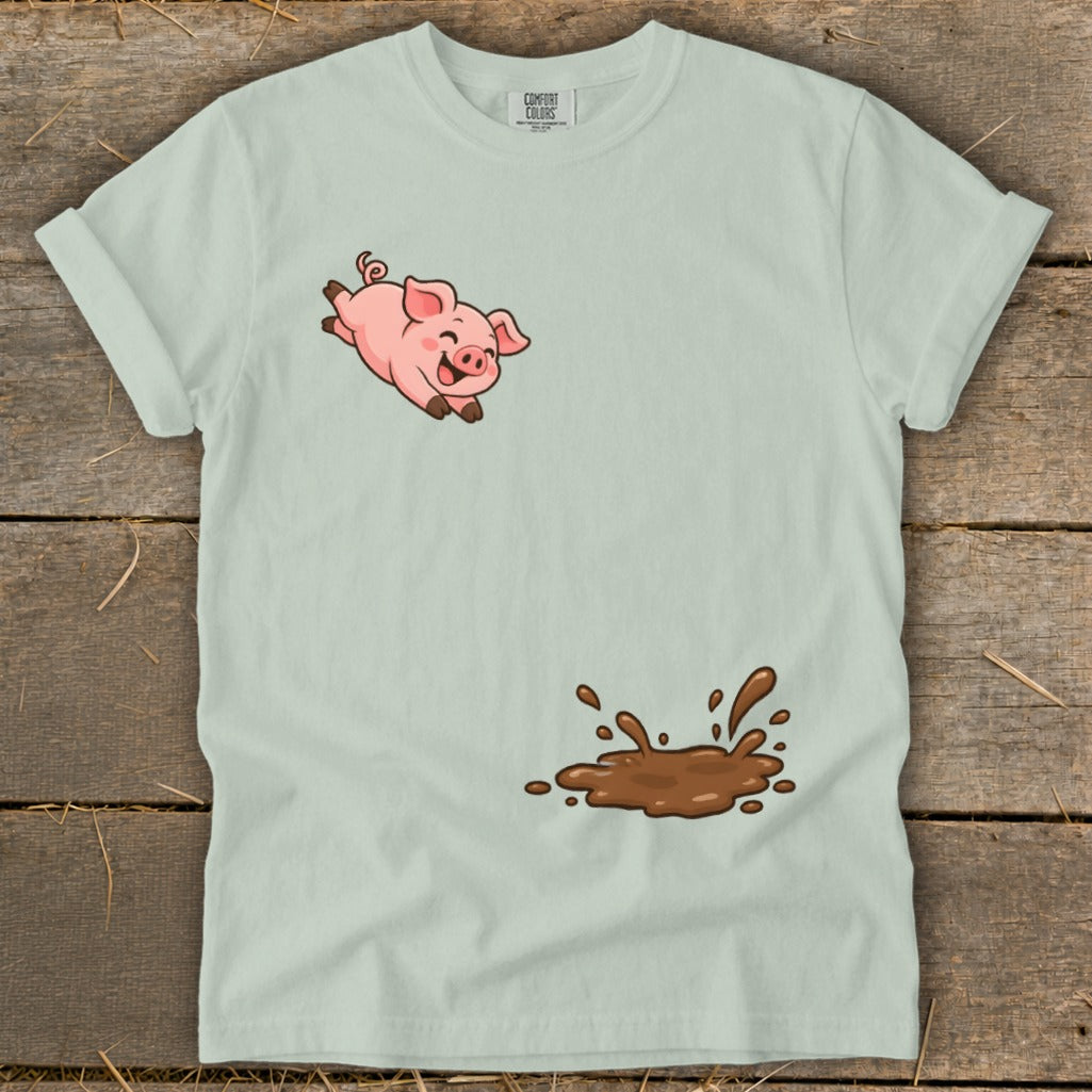 Light blue t-shirt with a cartoon pig jumping above a mud splash.