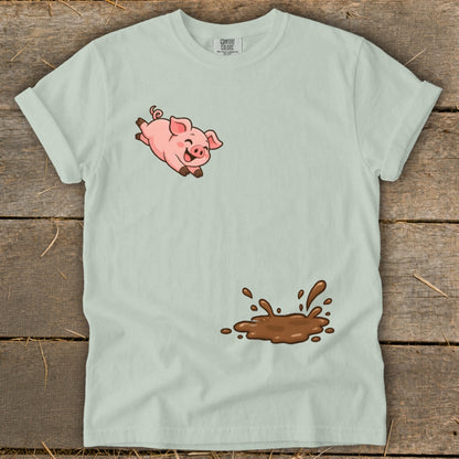 Light blue t-shirt with a cartoon pig jumping above a mud splash.