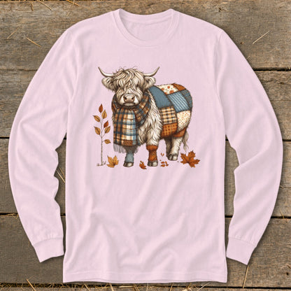 Highland cow wearing a plaid scarf and patchwork blanket, with autumn leaves.