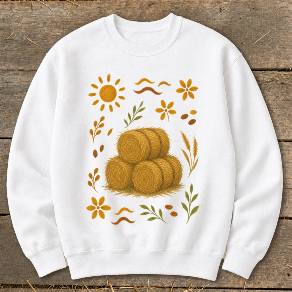 White sweatshirt with a stack of hay bales and autumn-themed graphics.