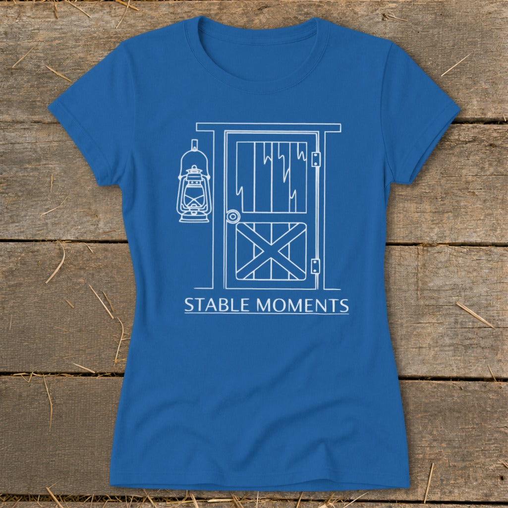 Blue t-shirt with white line drawing of a barn door and lantern, text "STABLE MOMENTS".