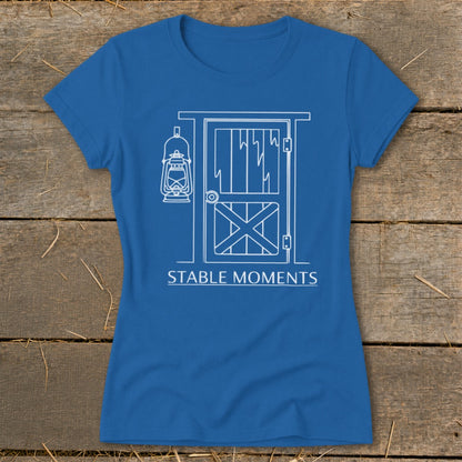 Blue t-shirt with white line drawing of a barn door and lantern, text "STABLE MOMENTS".