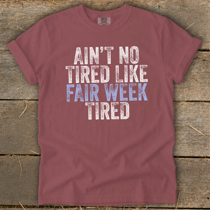 Maroon t-shirt with "Ain't No Tired Like Fair Week Tired" graphic text.