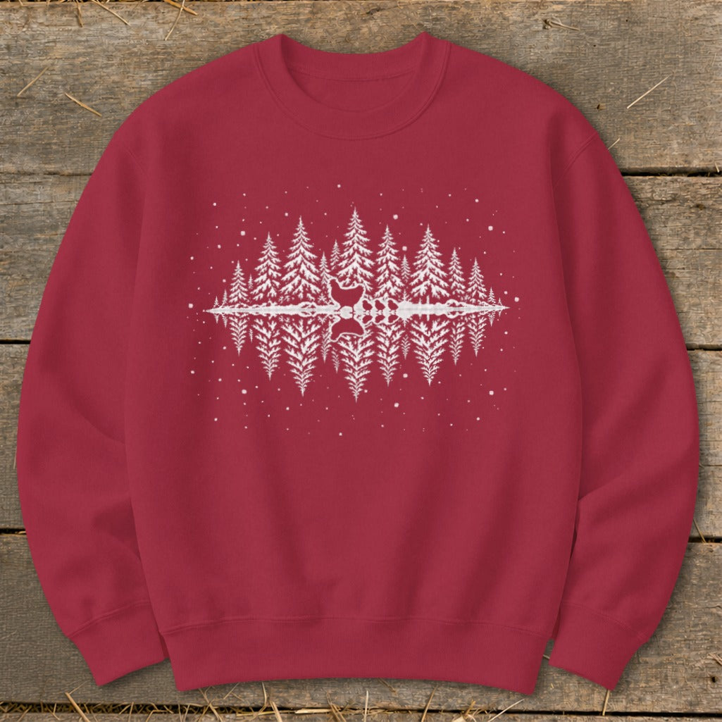Maroon sweatshirt with a white pine tree forest graphic with a reflection and falling snow.