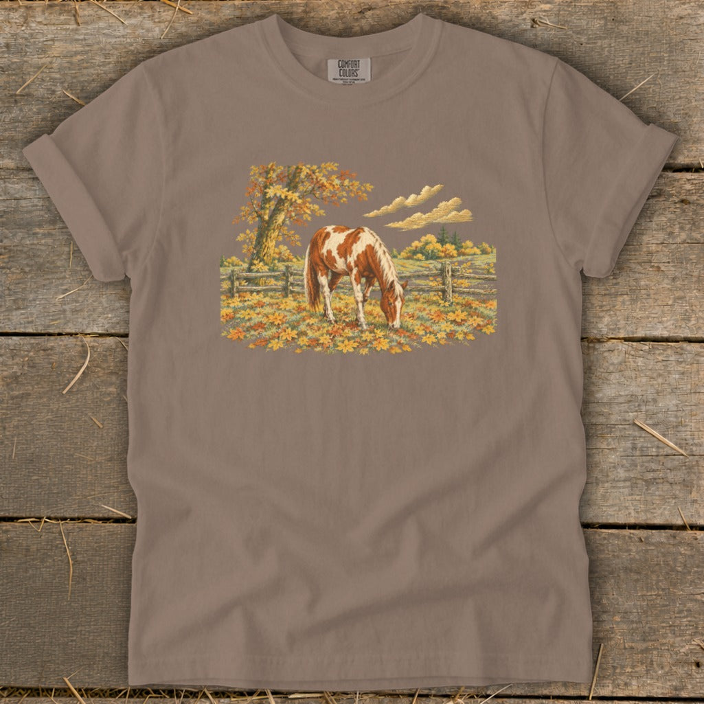 Brown t-shirt with Comfort Colors logo and a painted horse grazing in autumn leaves.