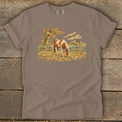 Brown t-shirt with Comfort Colors logo and a painted horse grazing in autumn leaves.