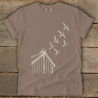 Brown crewneck t-shirt featuring a white line drawing of a barn and flock of swallows flying upward.