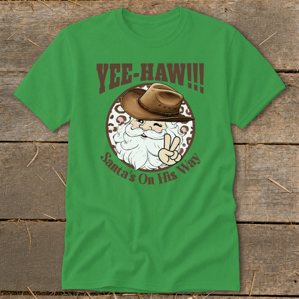 Green t-shirt with Santa in a cowboy hat, winking and giving a peace sign. Text reads "Yee-Haw!!!" and "Santa's On His Way".
