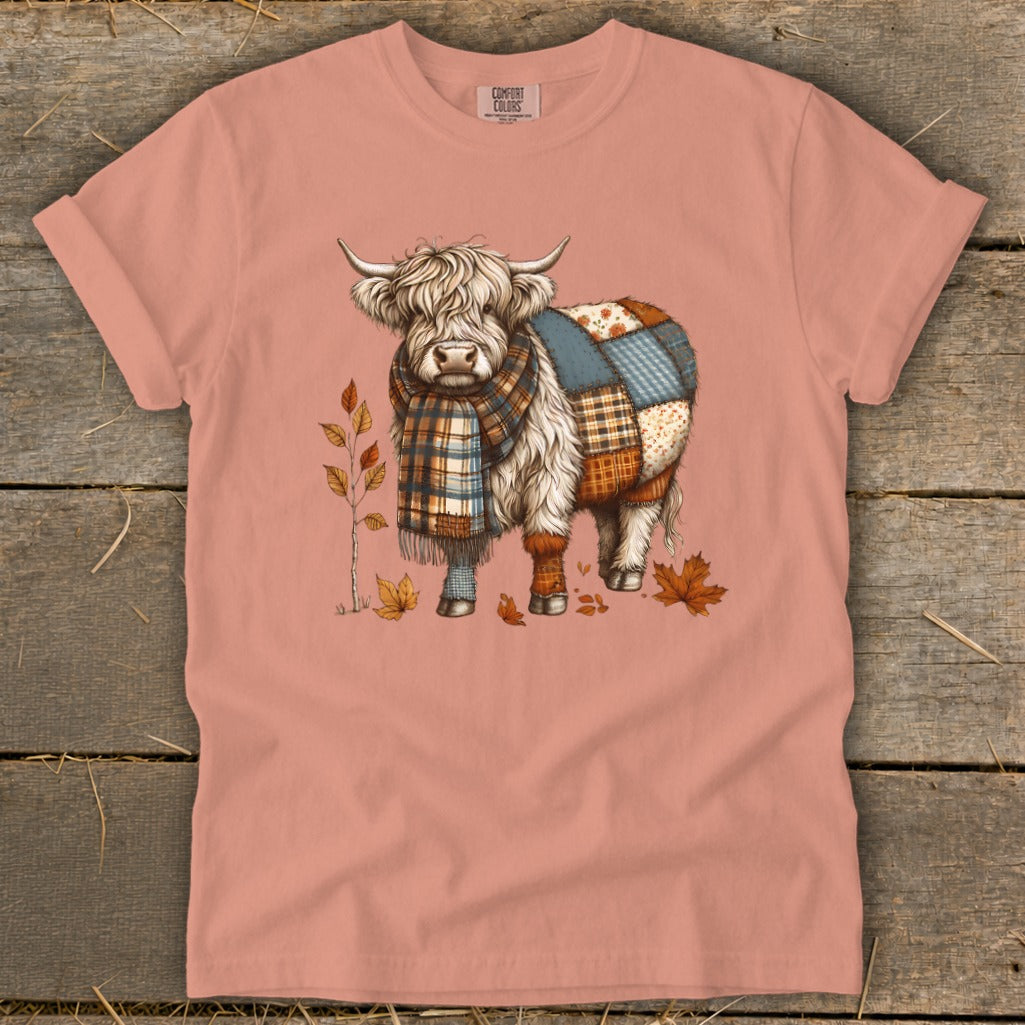 Highland cow wearing a plaid scarf and patchwork body, surrounded by autumn leaves.