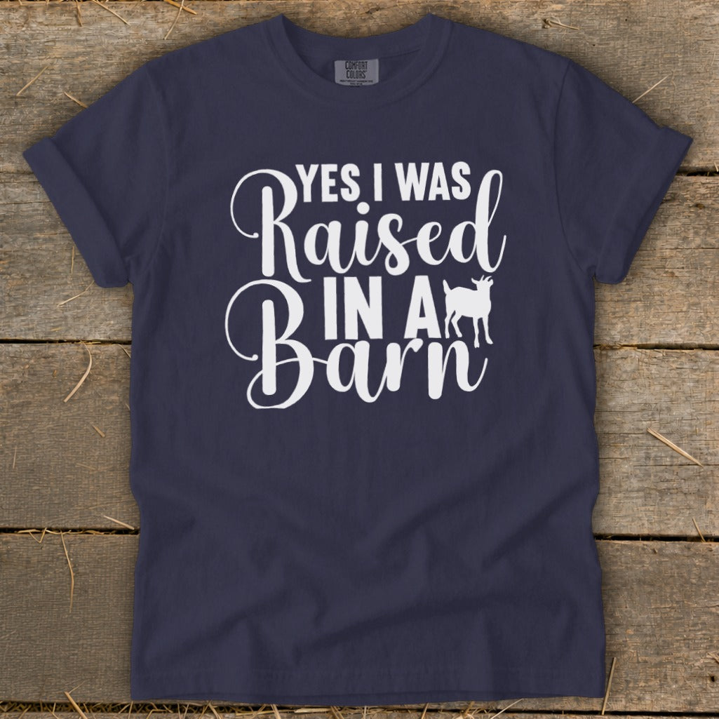 Navy t-shirt with white text reading "YES I WAS Raised IN A Barn" and a goat silhouette.