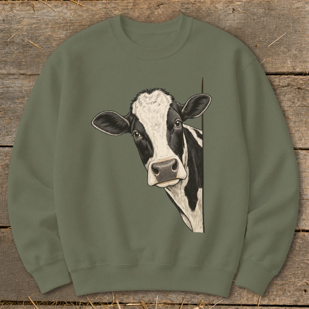 Black and white cow peeking from behind a green crewneck sweatshirt.